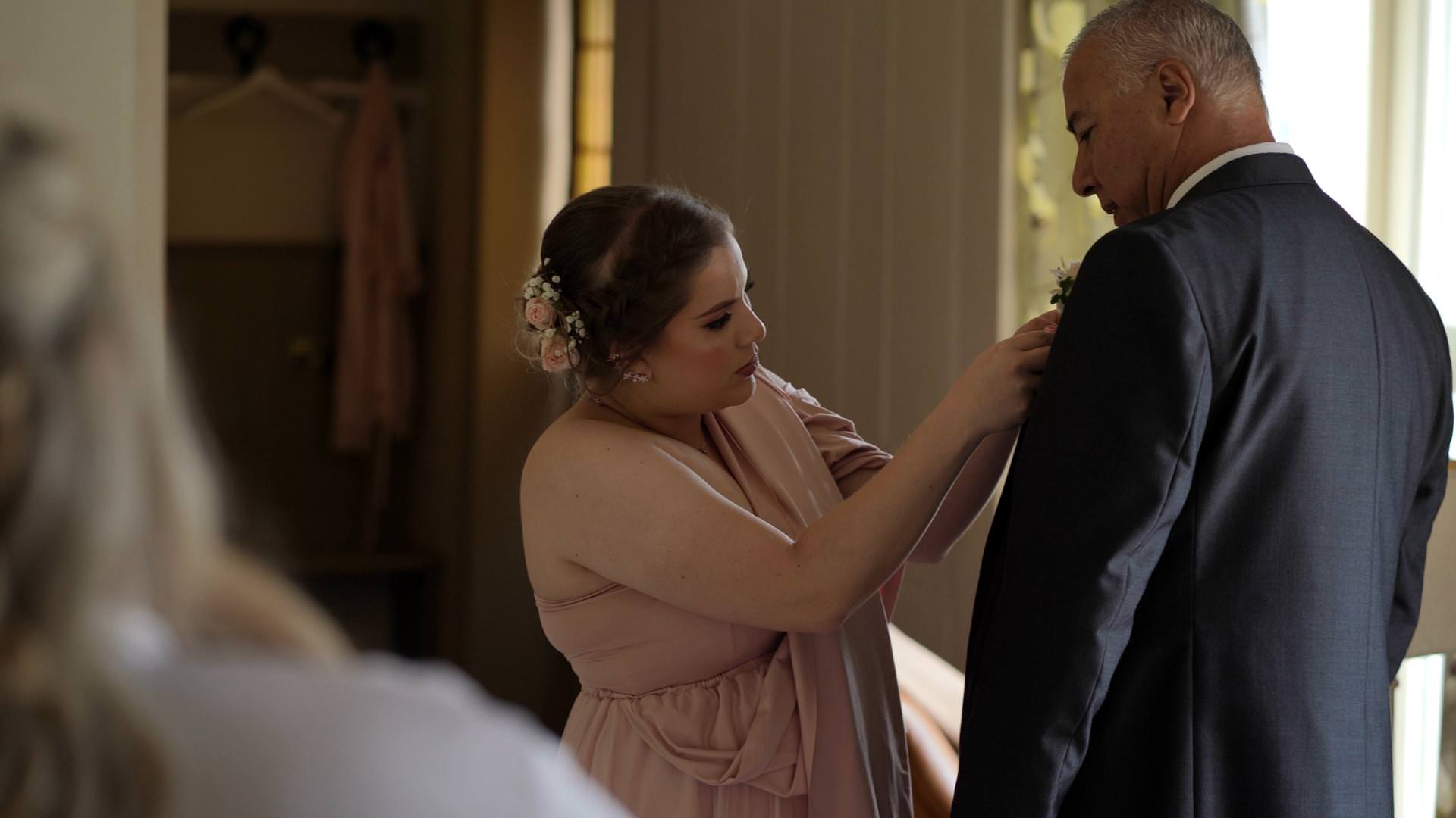 bridesmaid helps dad with buttonhole