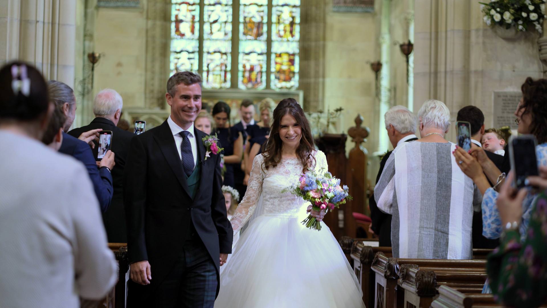 videographer films bride and groom leaving wedding ceremony