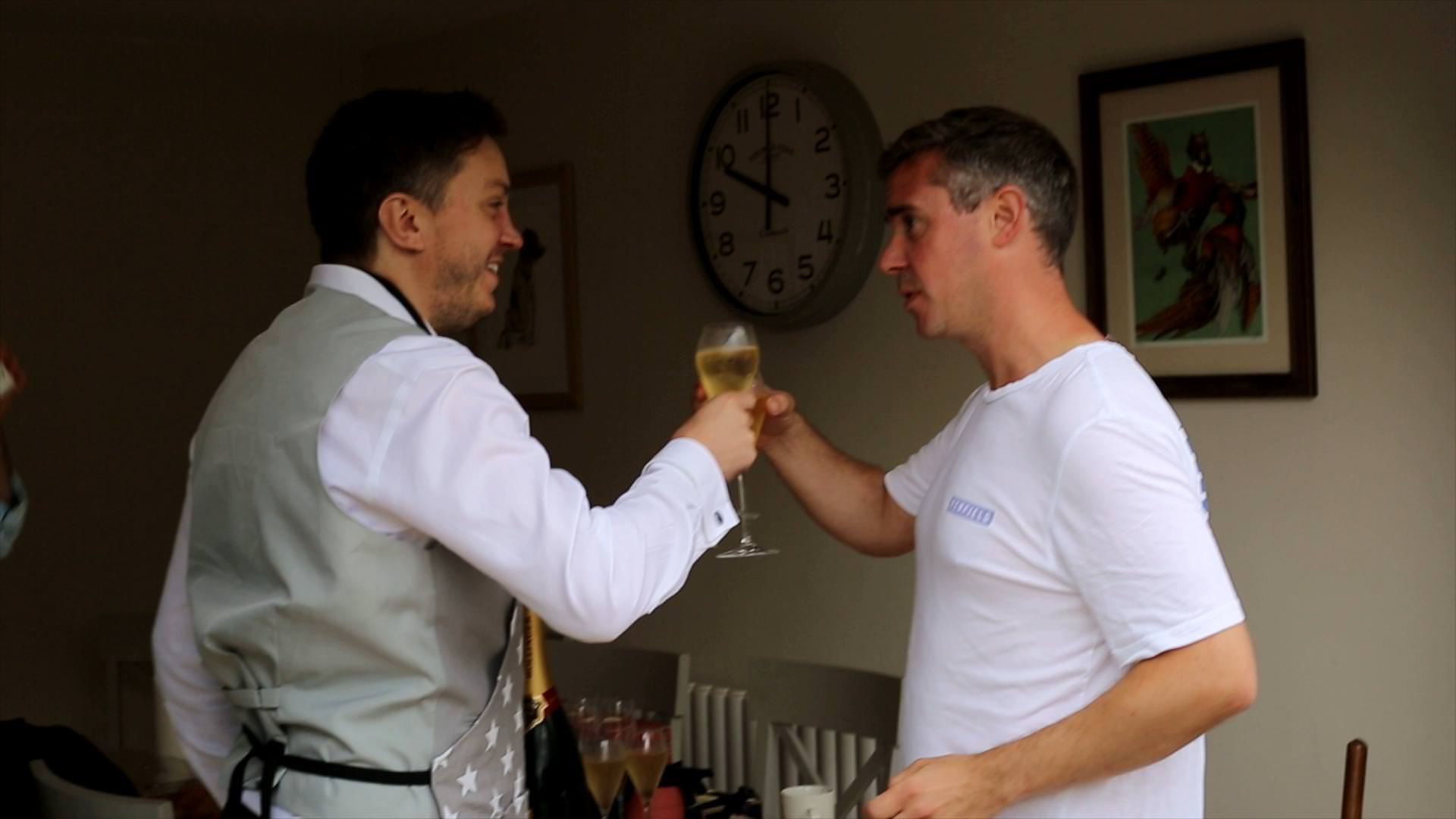 groom cheers champagne glass with groomsman