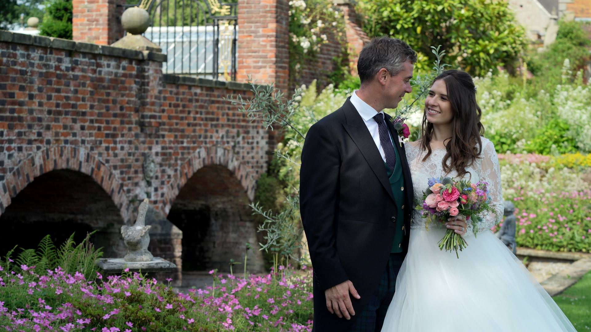 bride and groom smile in Barton Hall landscaped gardens