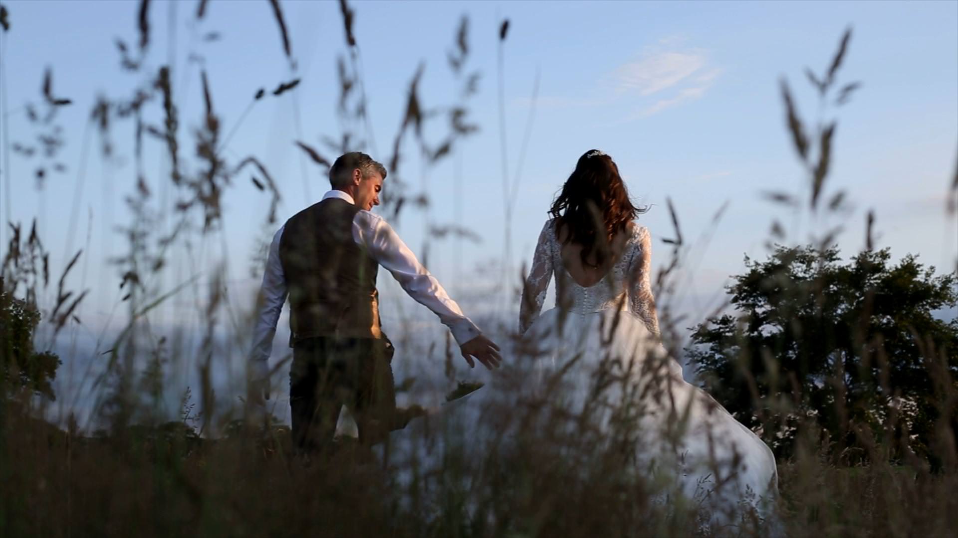 video of bride and groom walking through field