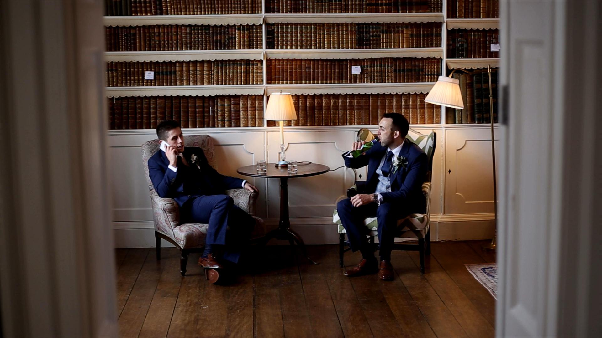 groom and best man relax in library at Iscoyd Park