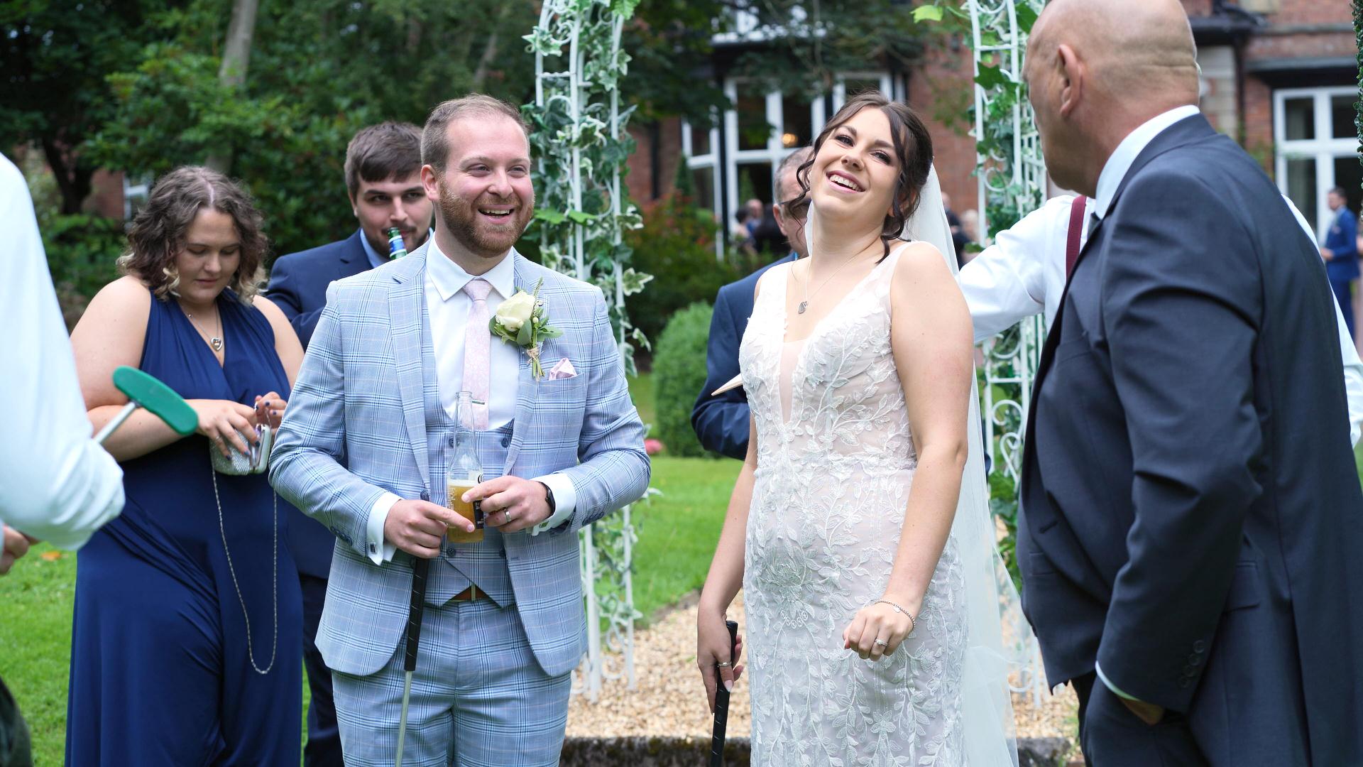 Rebecca and Nathan Ashfield House Wedding 16 couple laugh with golf clubs during crazy 9 mini golf at wedding
