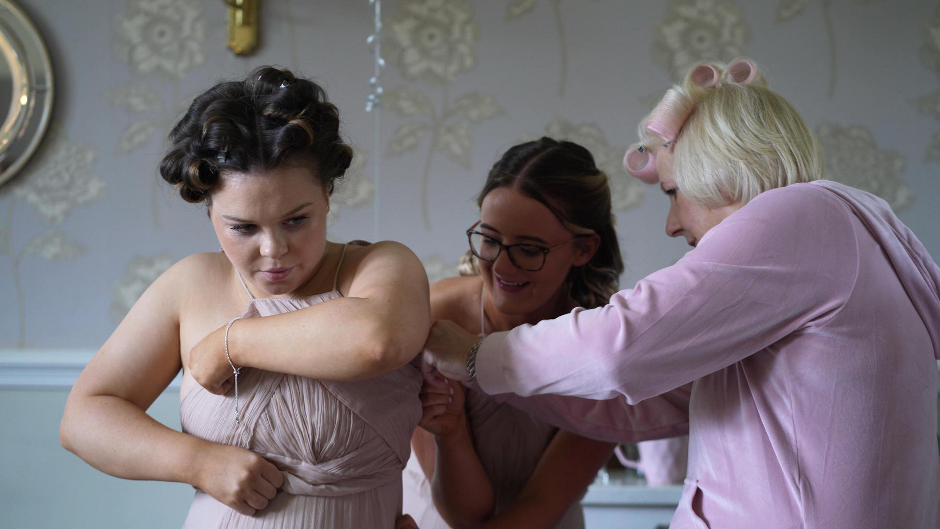 Rebecca and Nathan Ashfield House Wedding 4 bridesmaid getting help with her dress