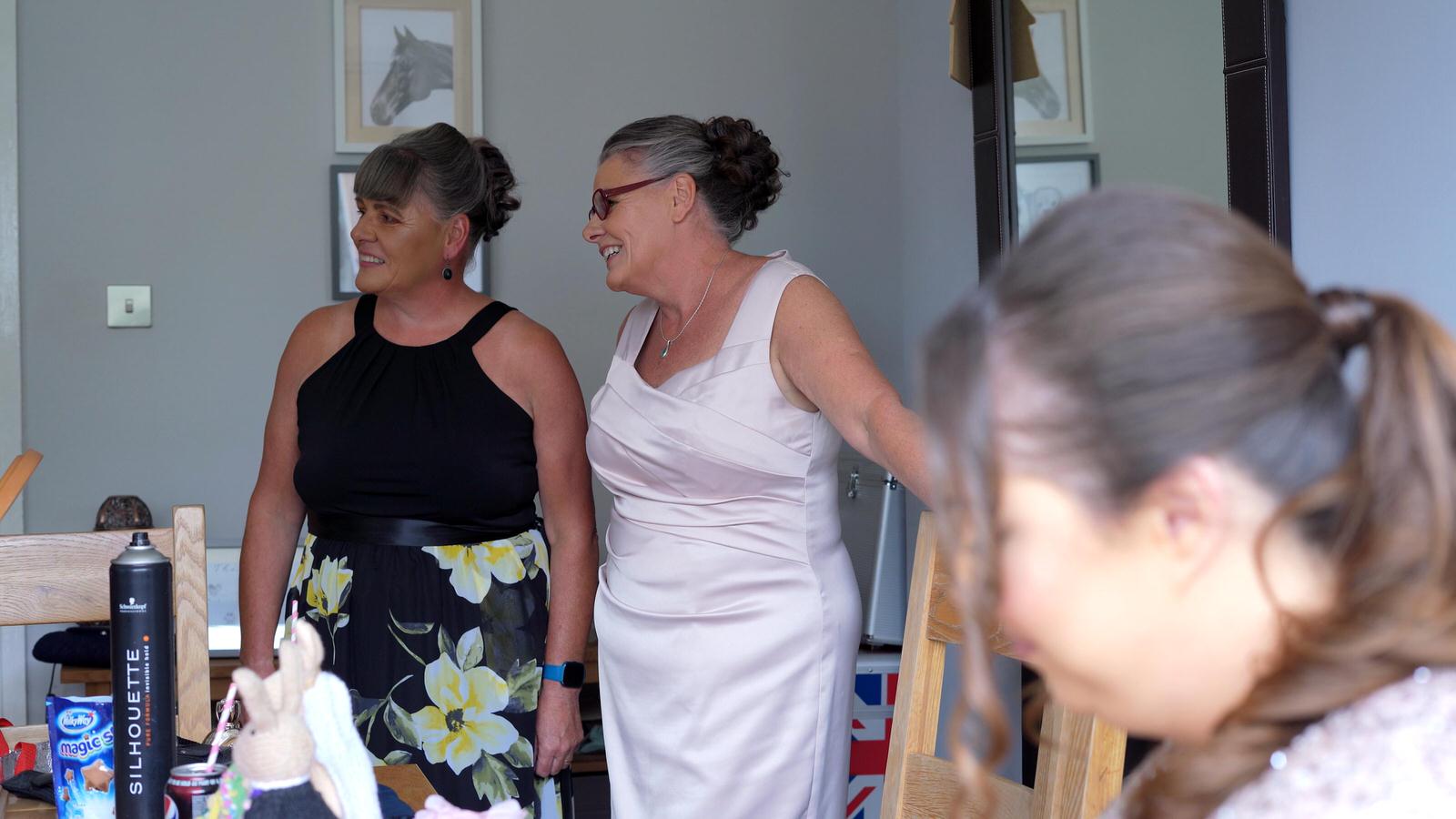 mother of the bride and twin sister smile at bride