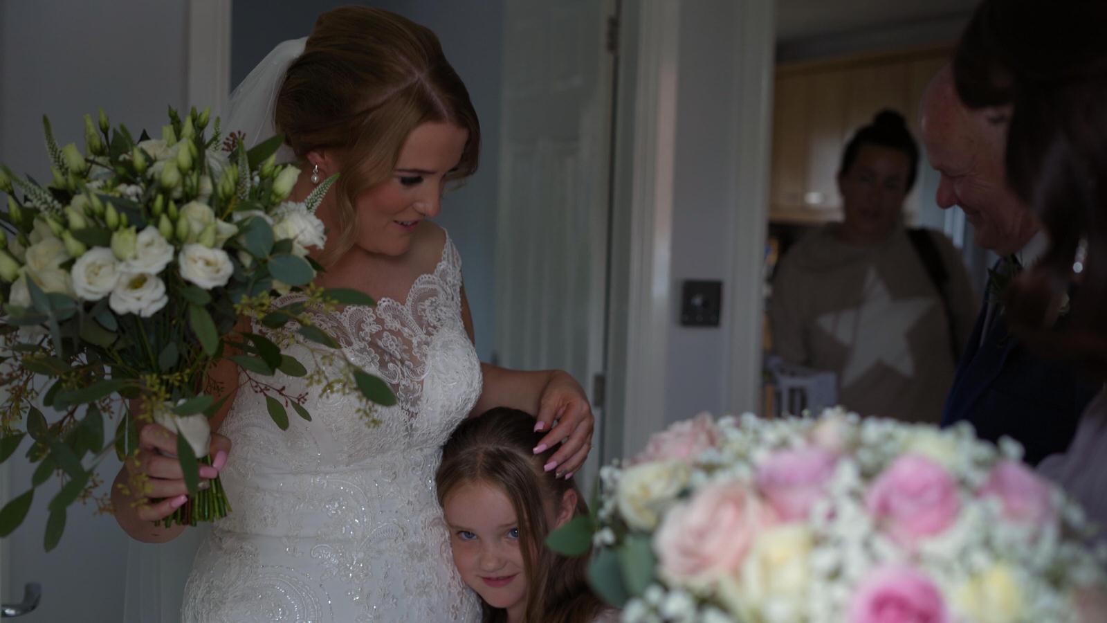 flowergirl hugs bride before leaving to the ceremony