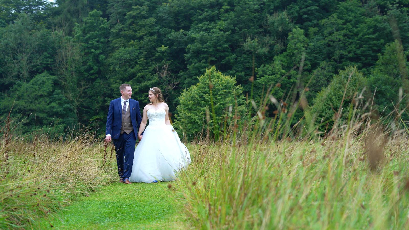 couple walk through long grass at Inn At Whitewell
