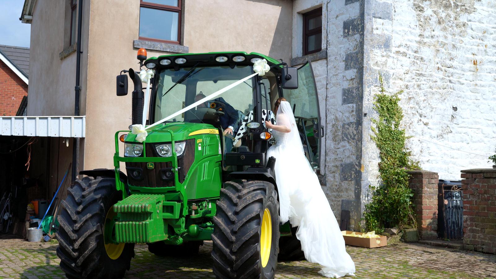 bride climbs in to her alternative wedding tractor