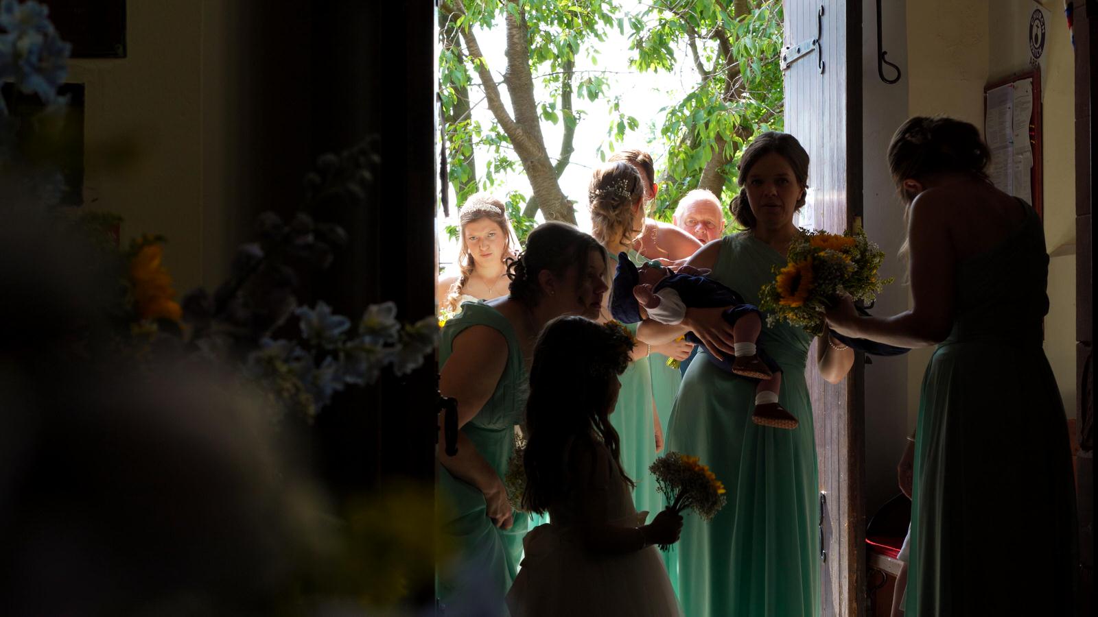 bride and bridesmaids wait inside Barton Church