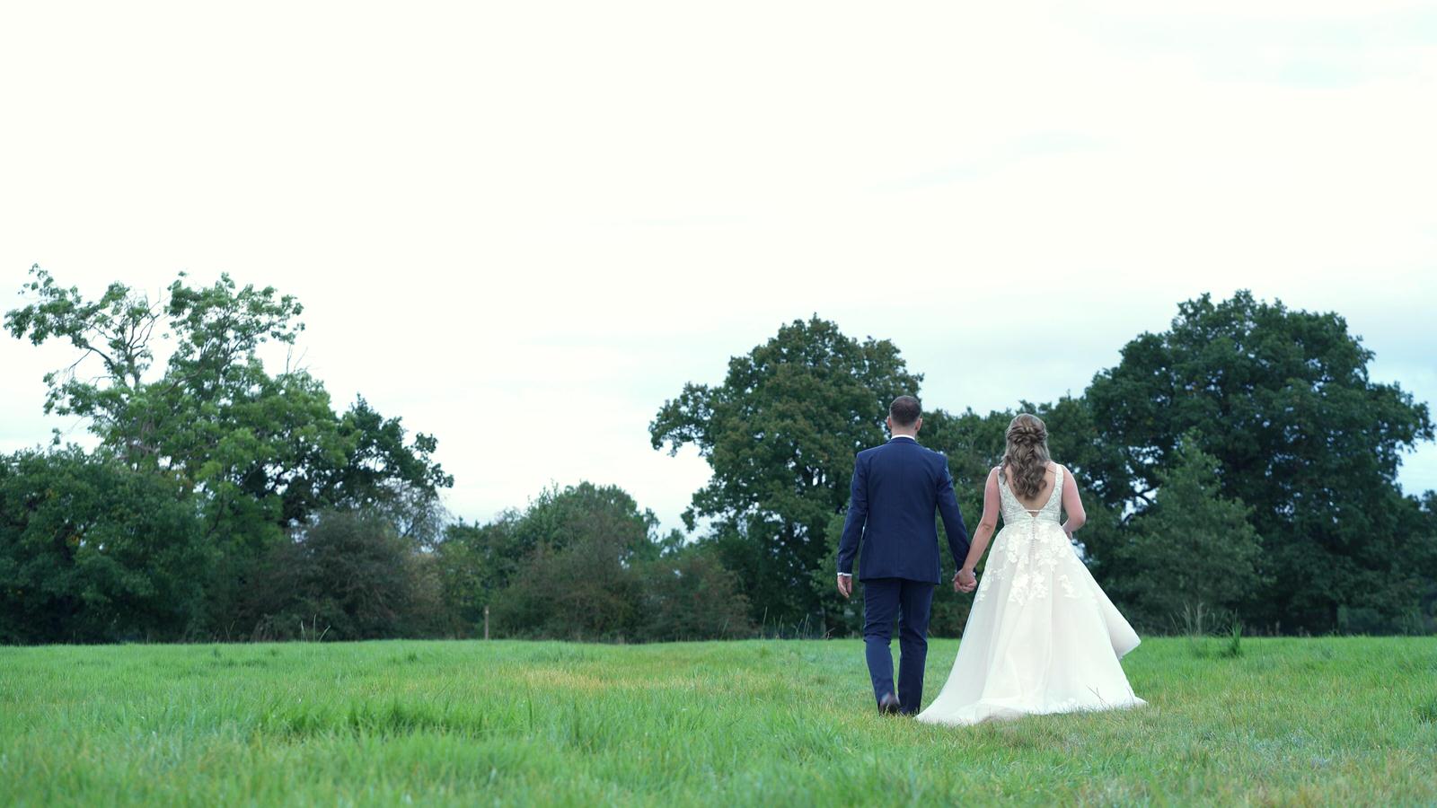 married couple walk through field near Owen House Barn
