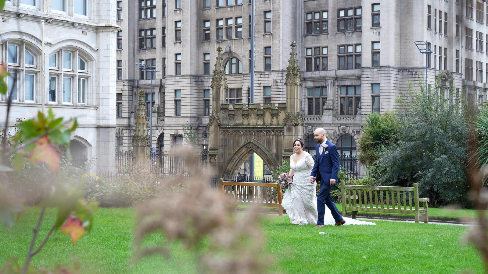 couple walk through gardens near iconic liver buildings