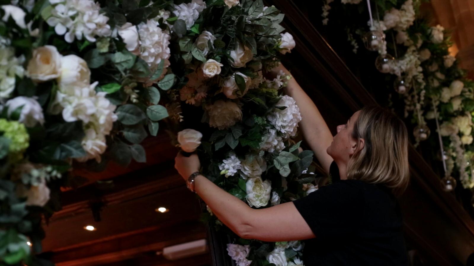 florist adds rose to flower arch at peckforton castle