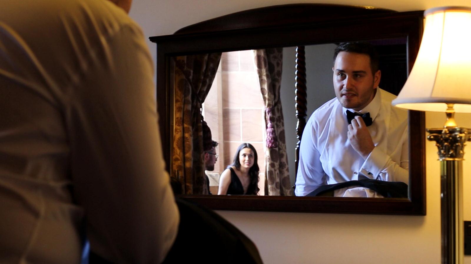 groom checks bow tie in mirror
