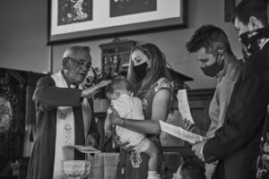priest pours holy water on baby during christening