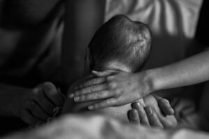 documentary photo of hands holding newborn baby