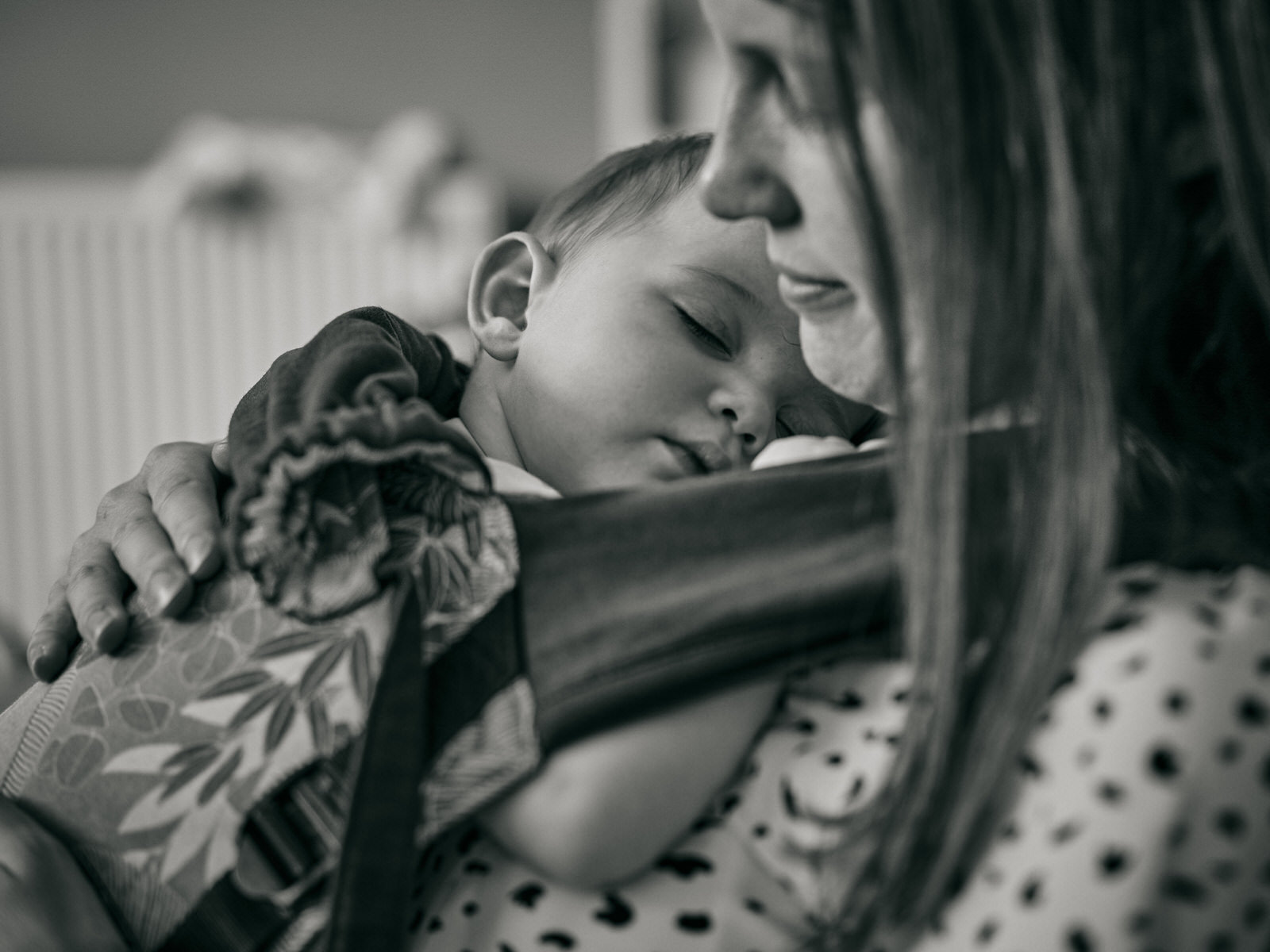 close up photo of baby in carrier asleep on mum