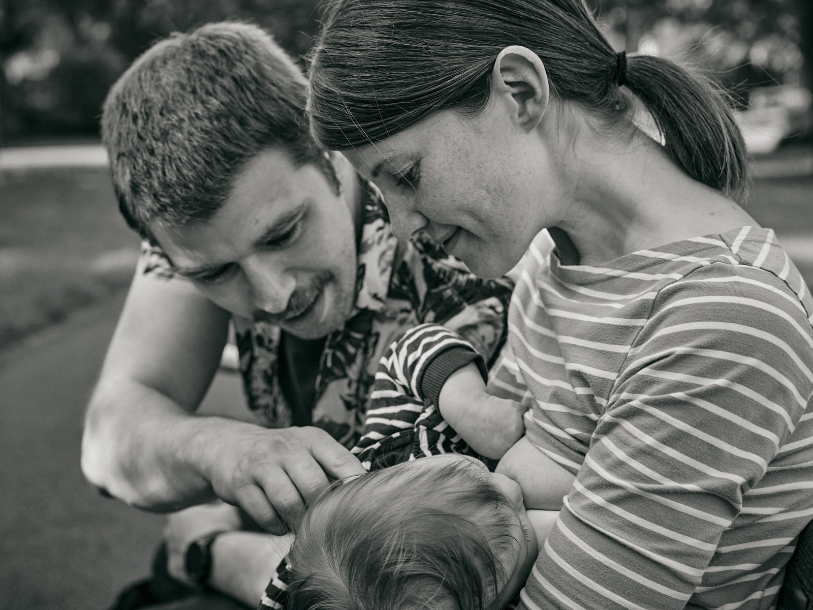 parents look lovingly at baby as they breastfeed