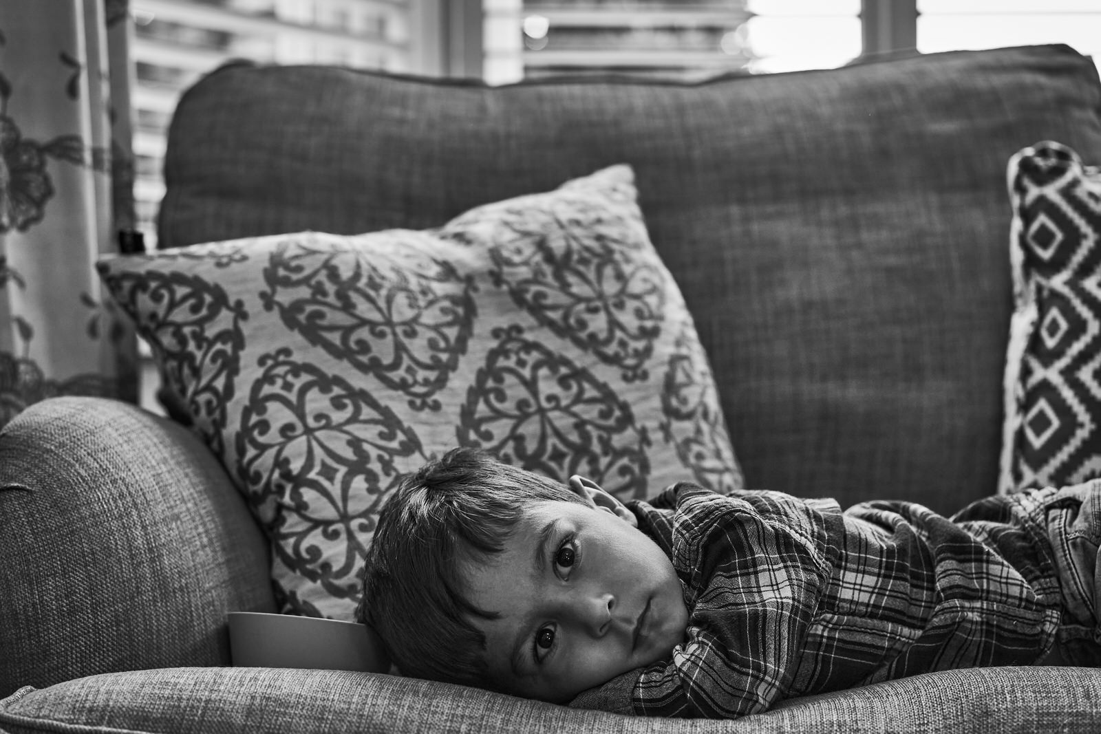 toddler lays on sofa and looks at camera