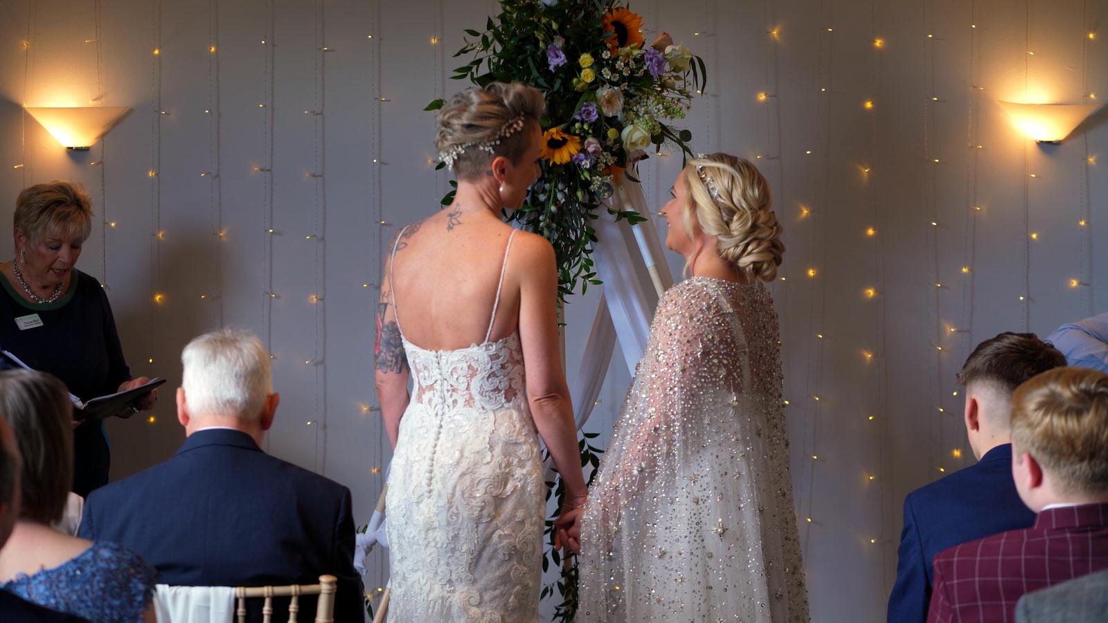 two brides smile at each other during ceremony at Chilli Barn