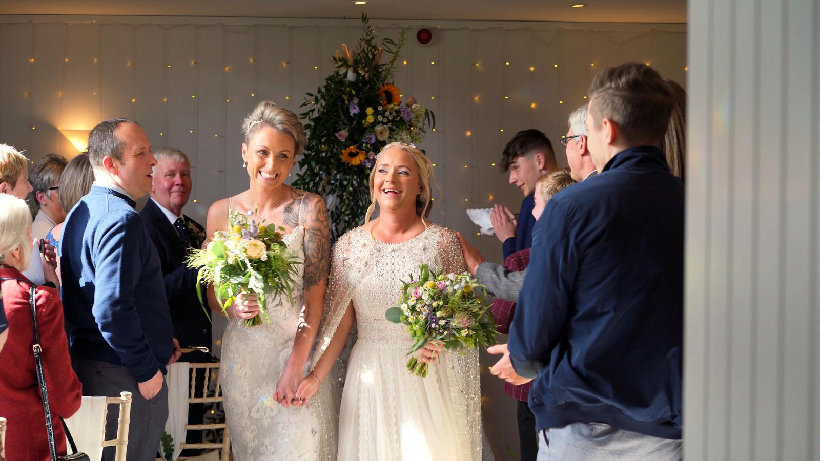 two brides walk down the aisle at Chilli Barn Otley