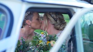 two brides kiss inside a classic mini for wedding video