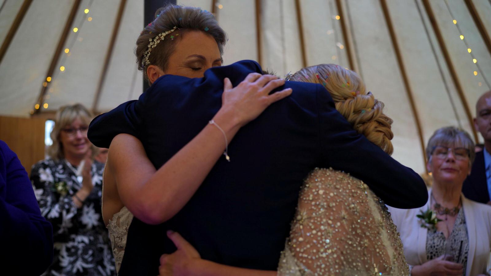 brides hug their son after wedding speech
