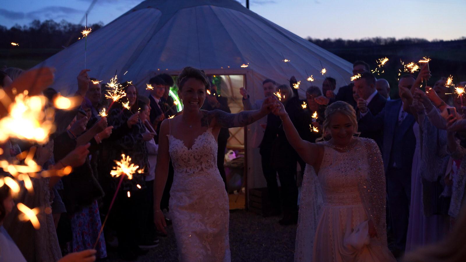 two brides race through confetti tunnel at Chilli Barn wedding
