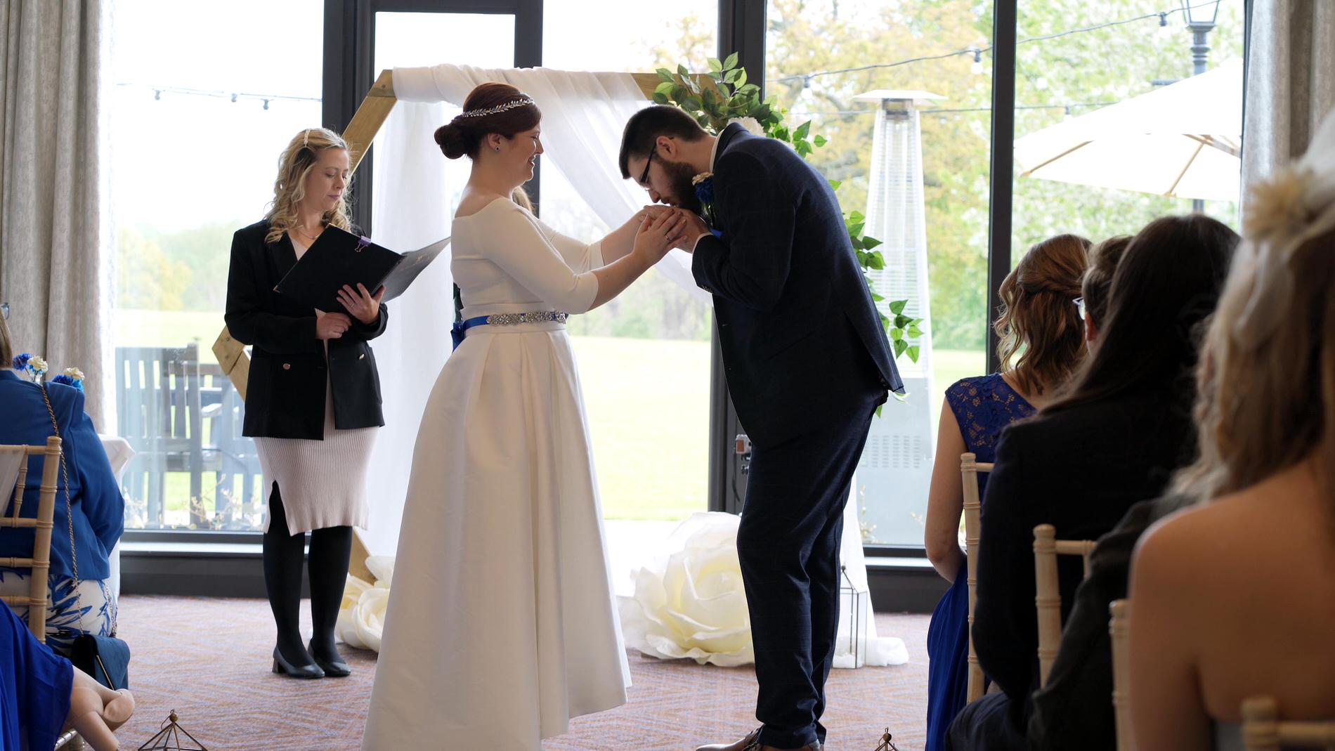 groom kisses brides hand during Rookery Hall ceremony
