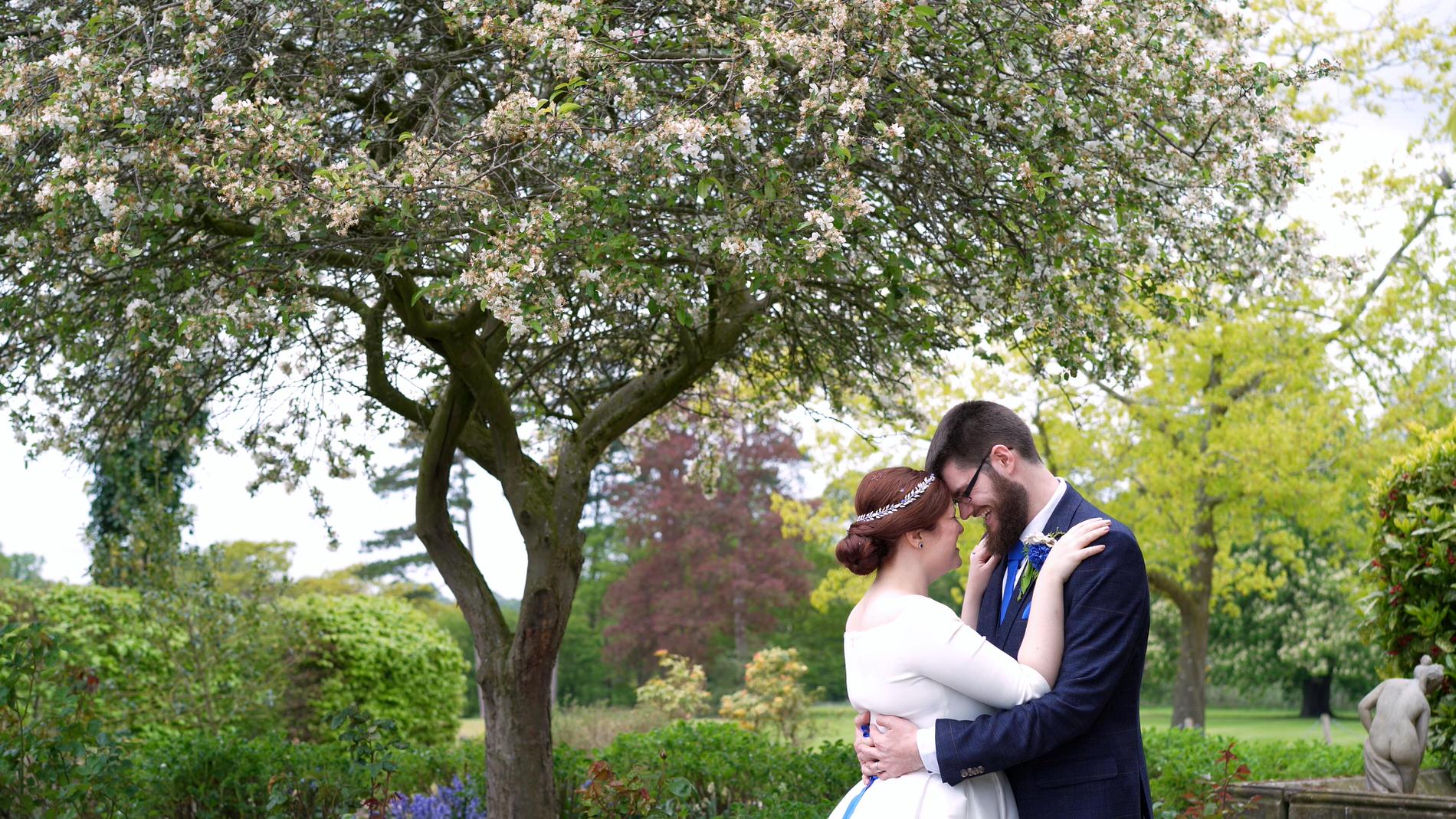 couple pose below a blossom tree in cheshire