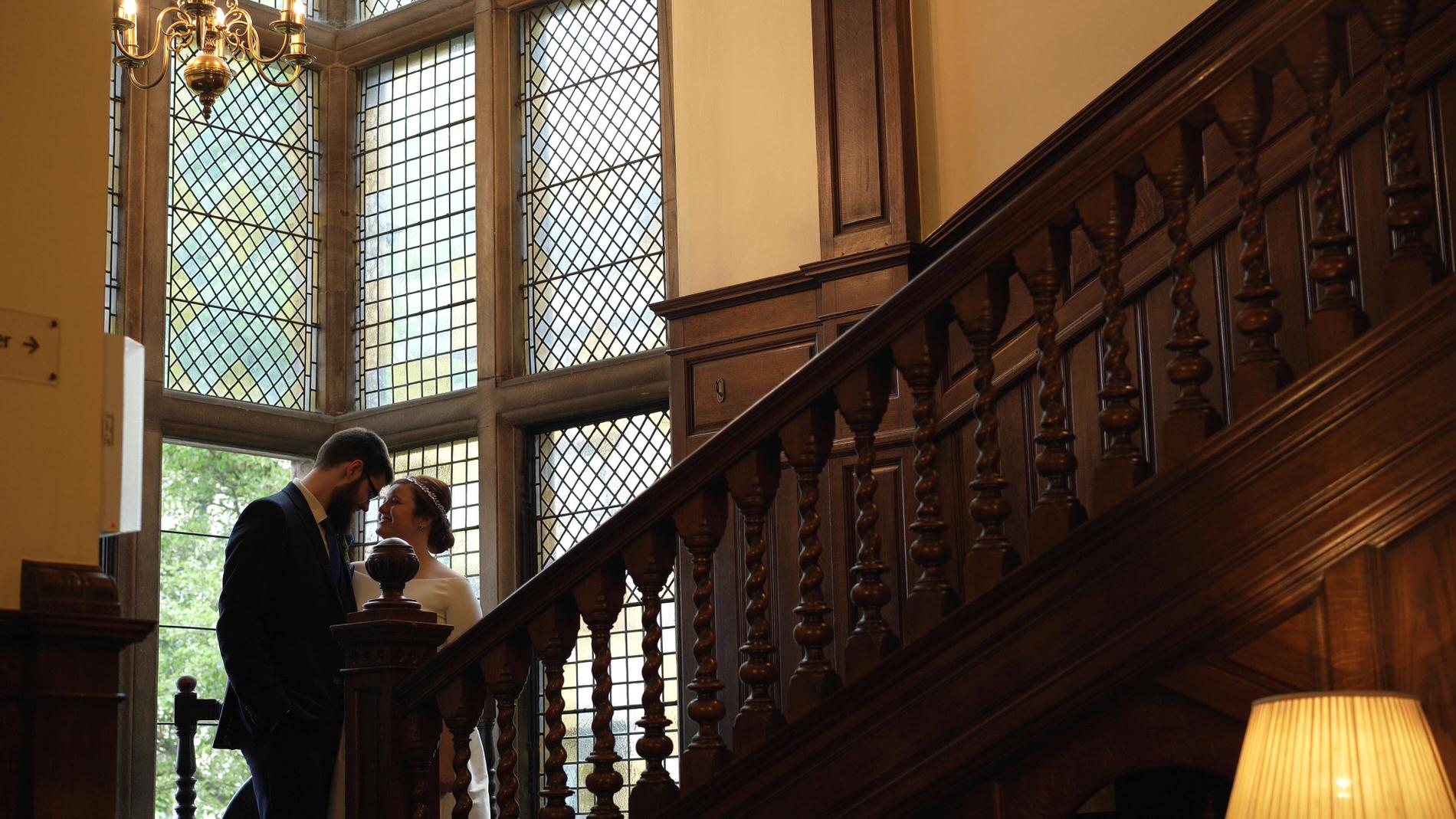 couple stand on Rookery Hall staircase for photos and video