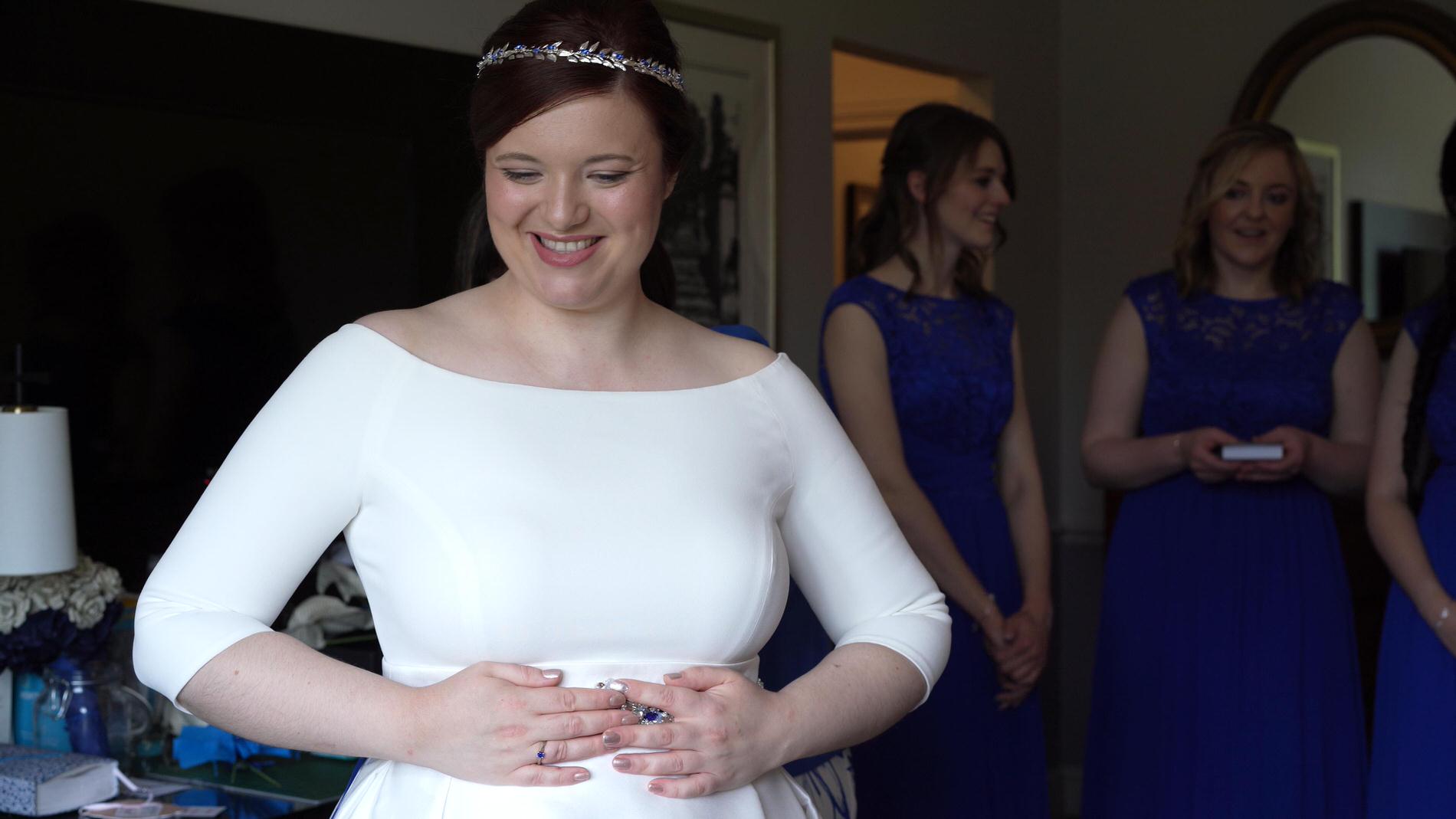bride smiles as she gets in to her wedding dress