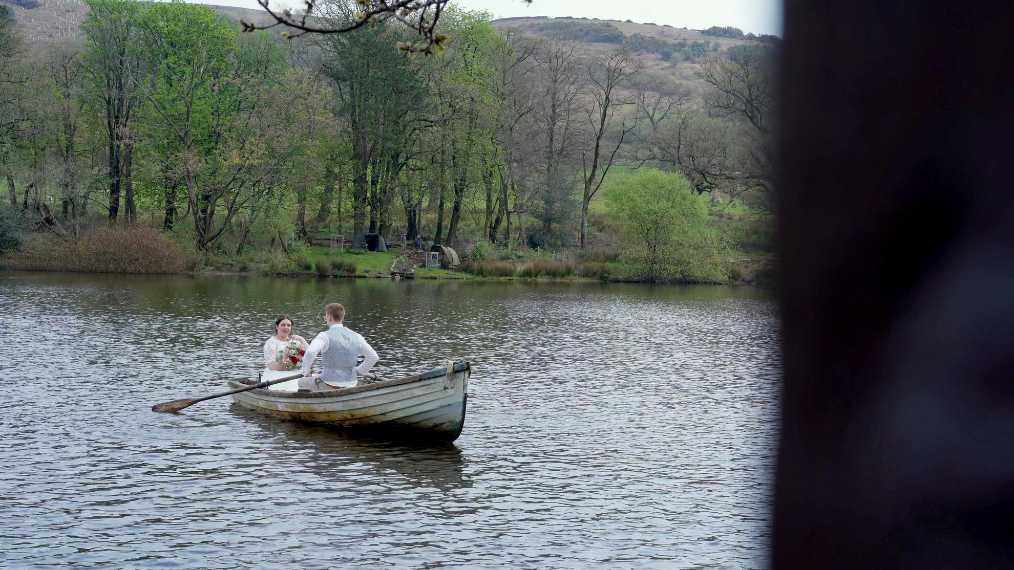a bride and groom sit in a boat on the lake at Wyresdale Park