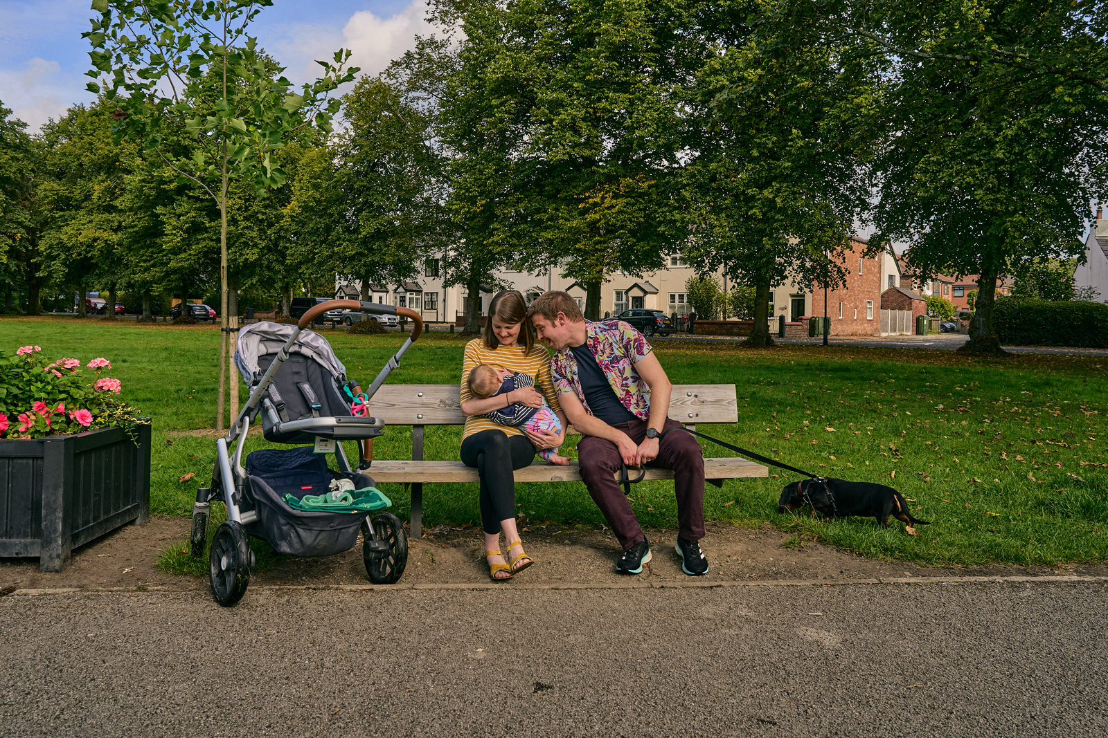 family sit on bench to breastfeed during photo shoot