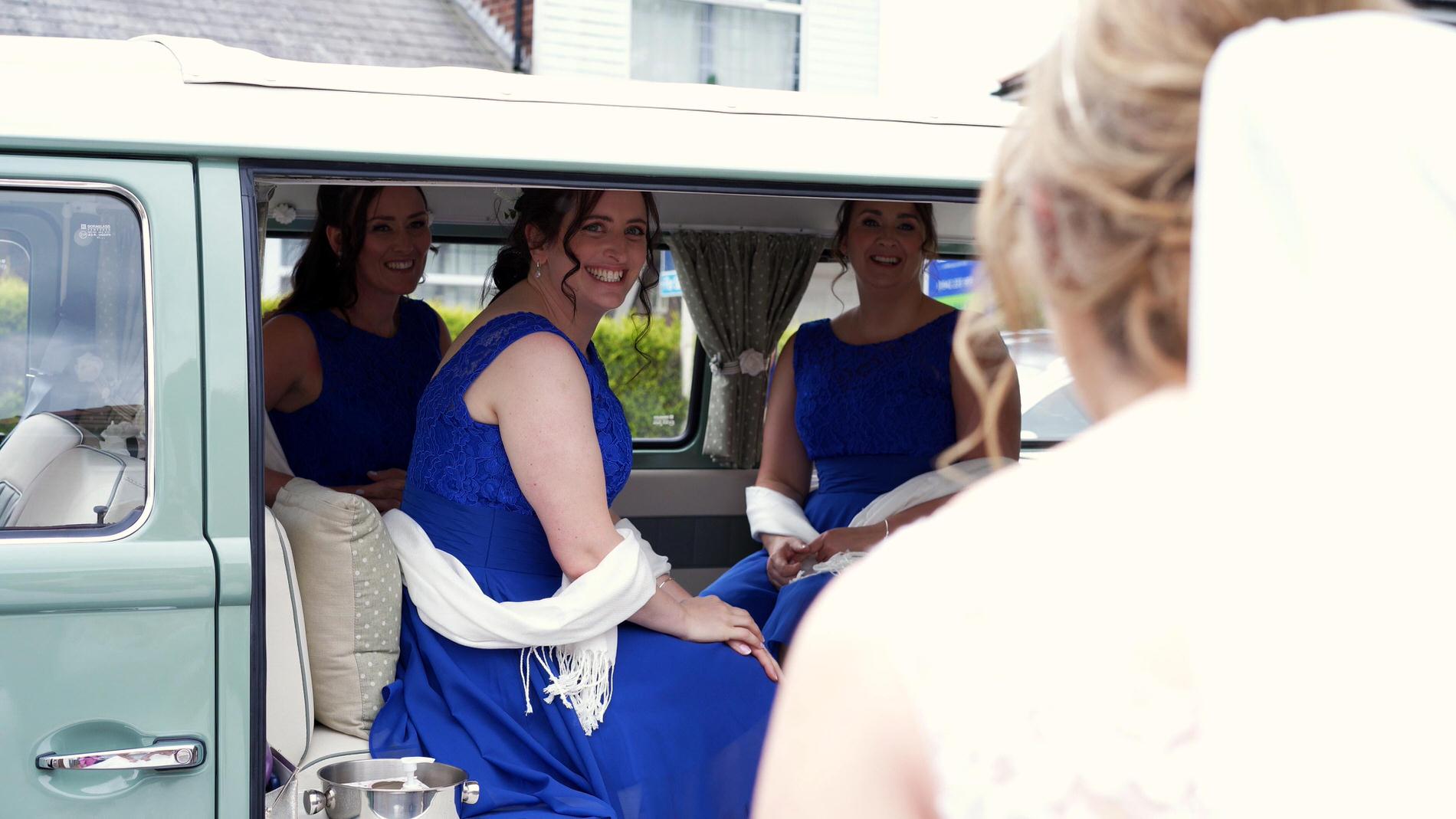 bridesmaids grin at bride from campervan