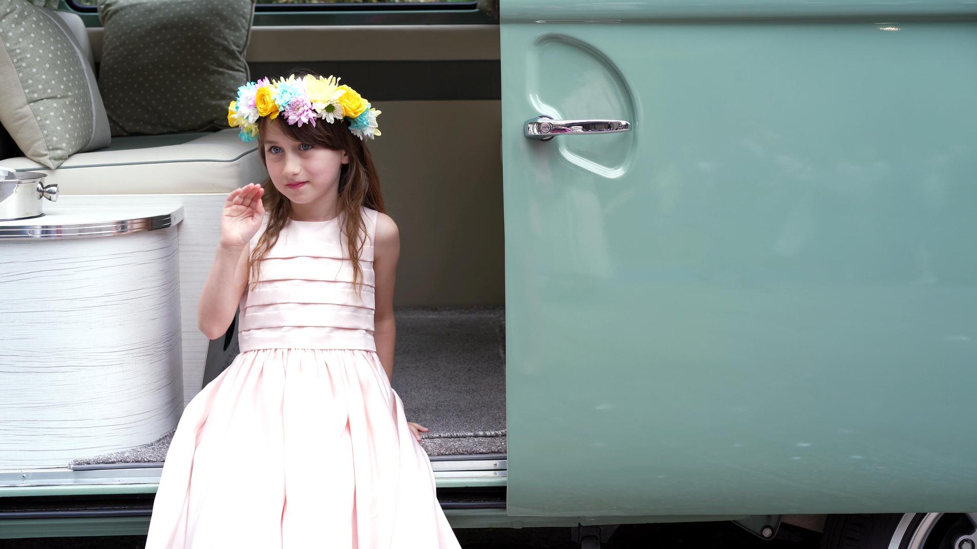 girl wears flower crown and sits in vintage camper