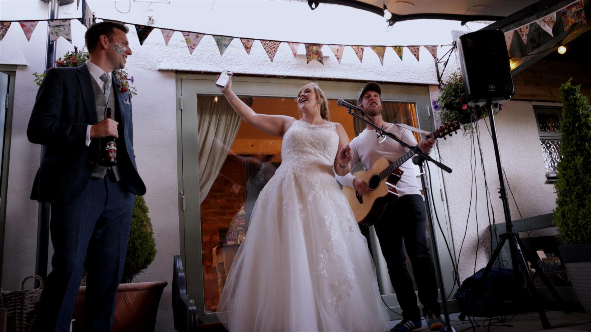 Bride sings along with acoustic singer during wedding at Roby Mill