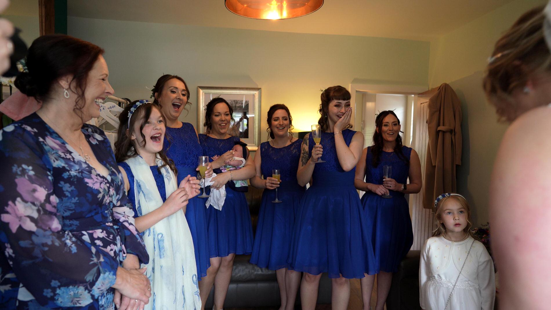 video still of bridesmaids reaction to bride in dress