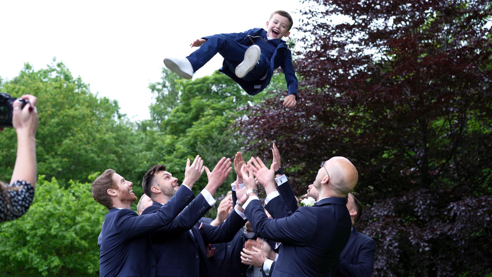 page boy thrown in the air during wedding