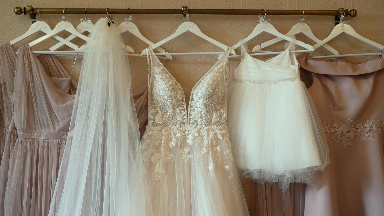 wedding dress and flower girl dress hang in bridal suite