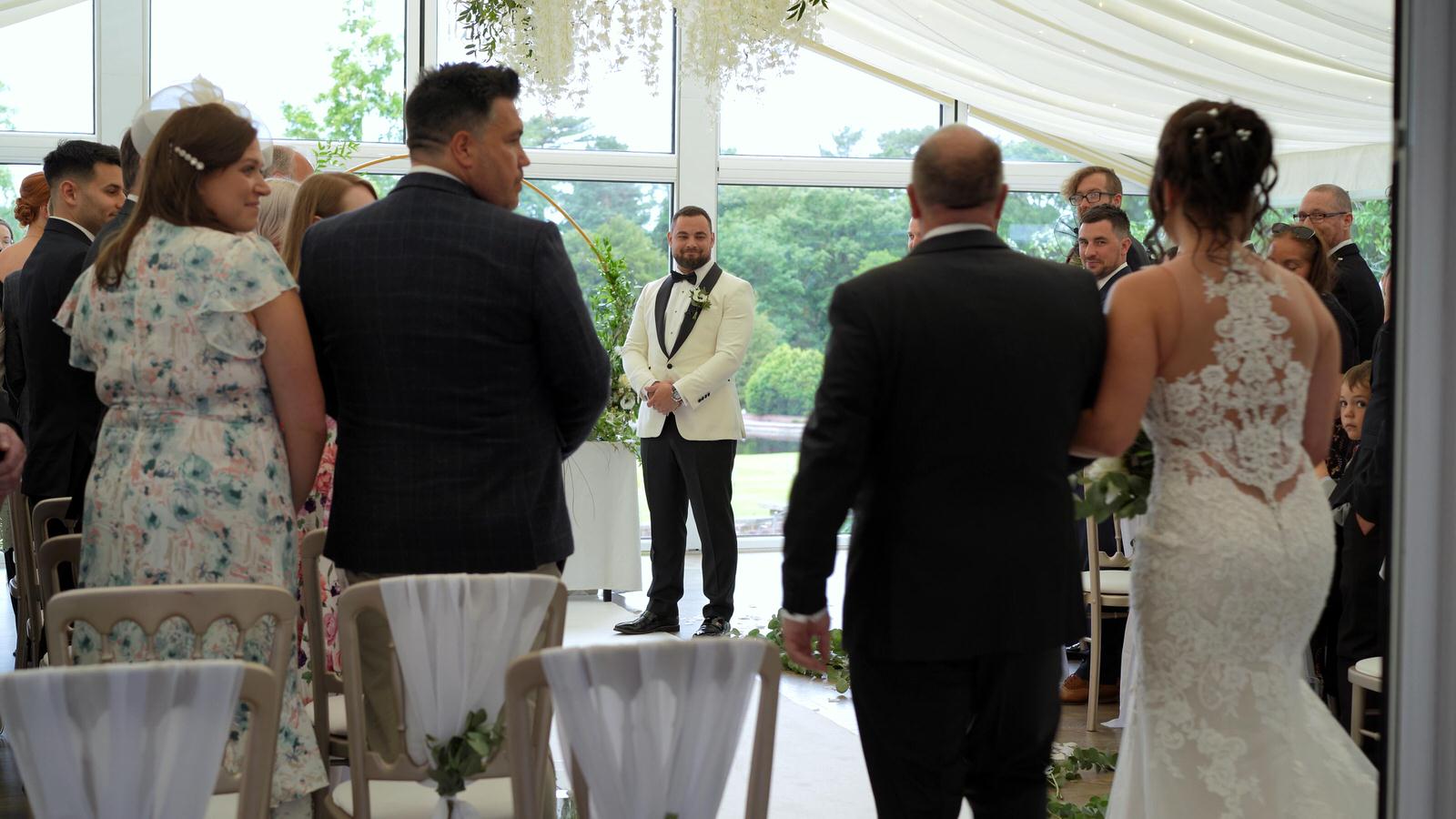 bride walks down aisle at Lakeside wing Capesthorne Hall