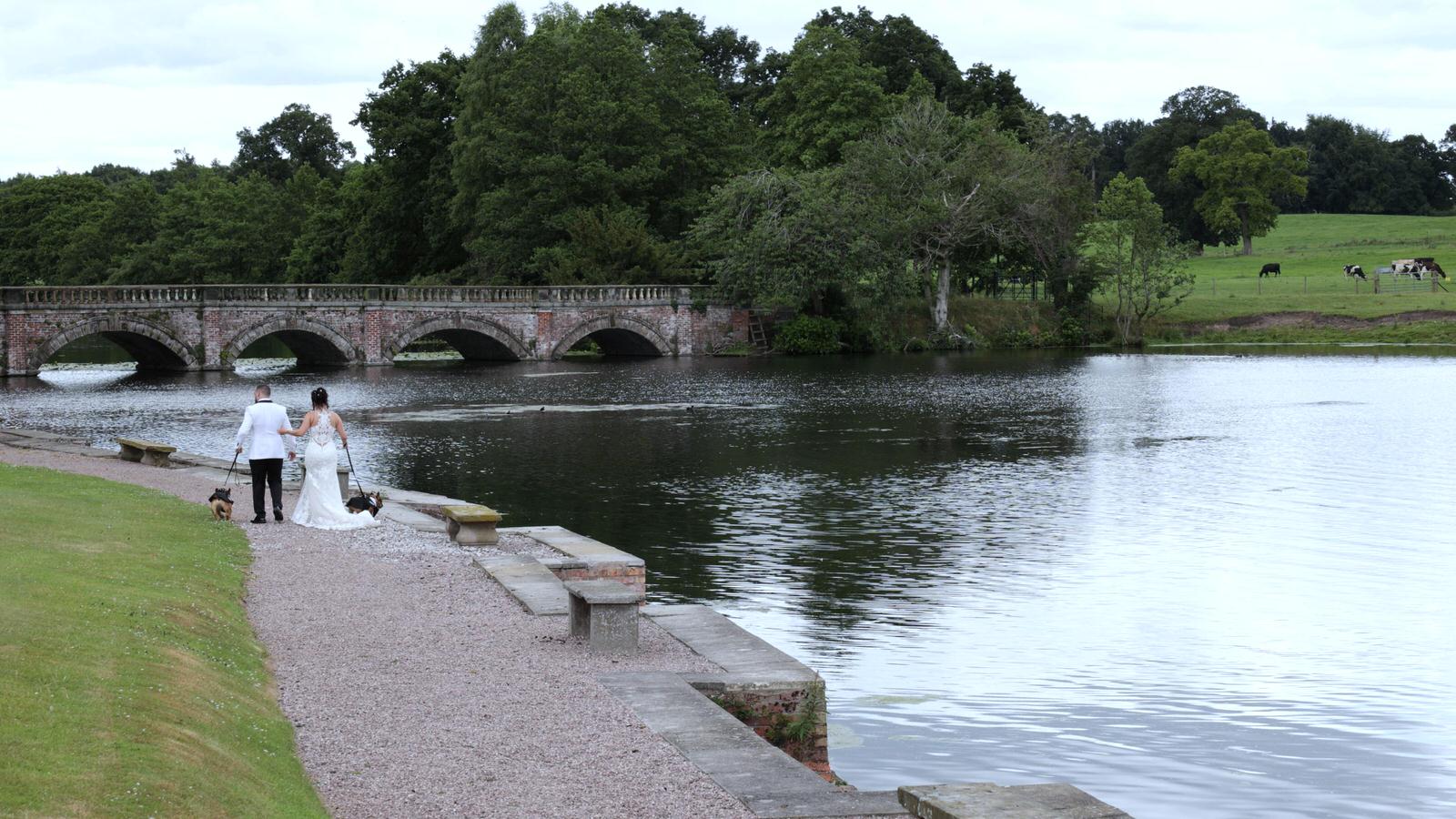 couple walk by lake at Capesthorne Hall