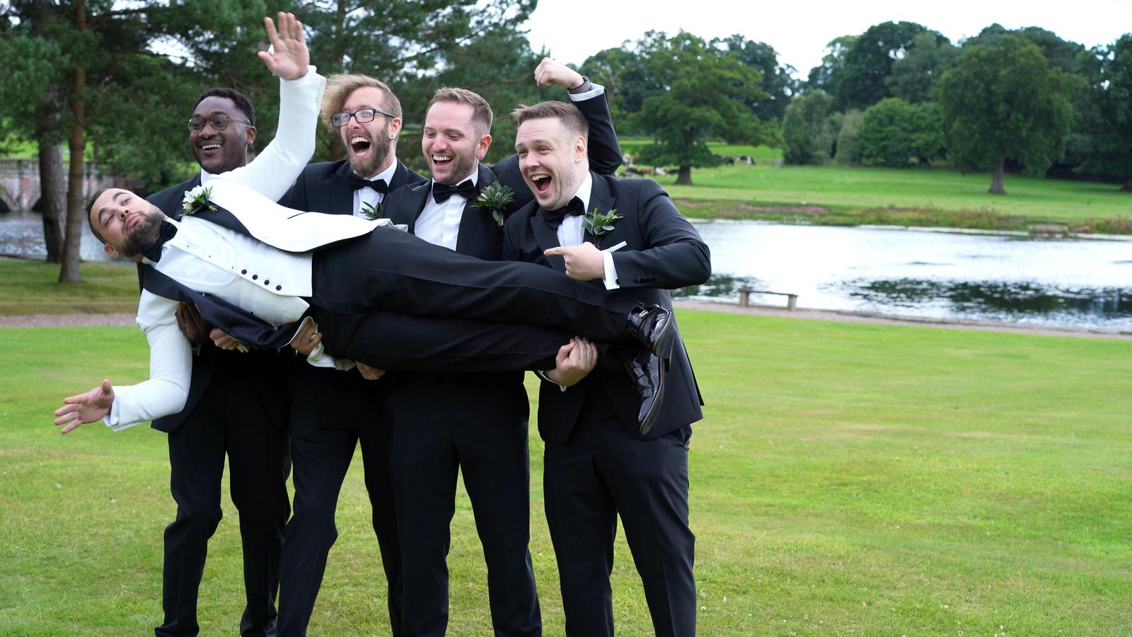 the groomsman lift the groom for a photo