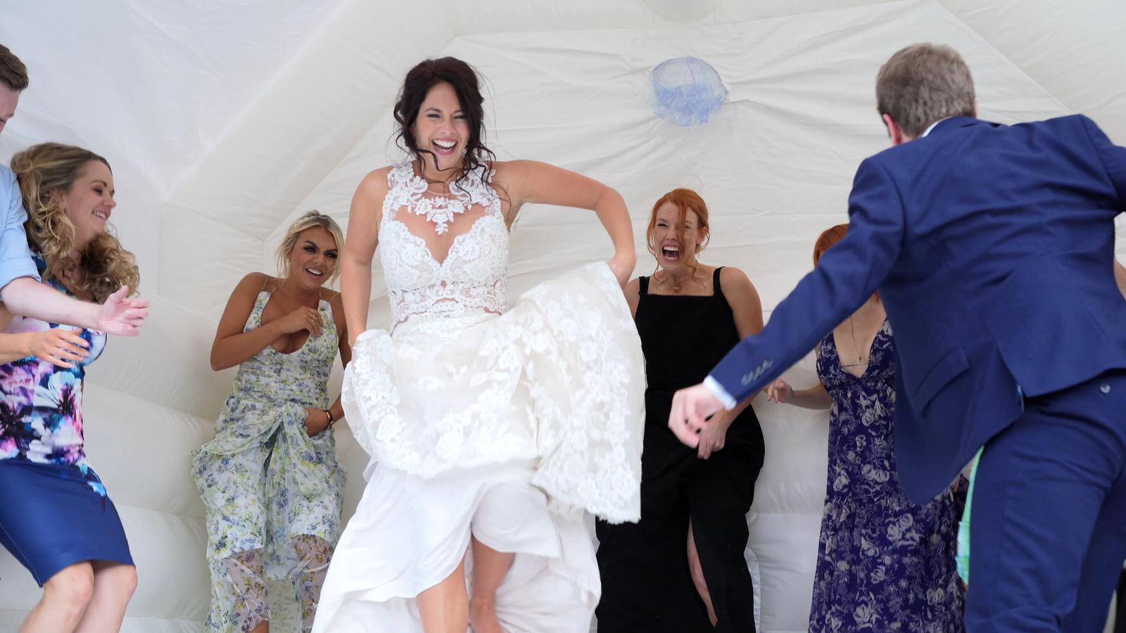 bride laughs bouncing on white wedding bouncy castle