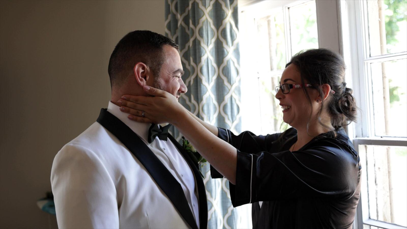 sister affectionately holds the grooms face