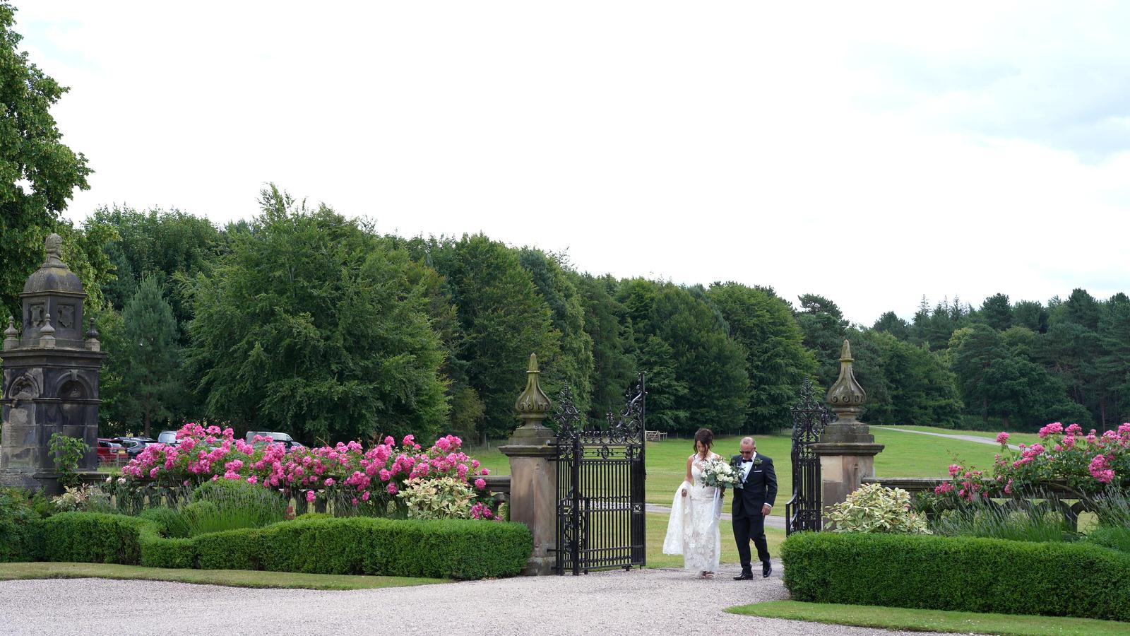 dad and bride walk through Capesthorne Hall gardens