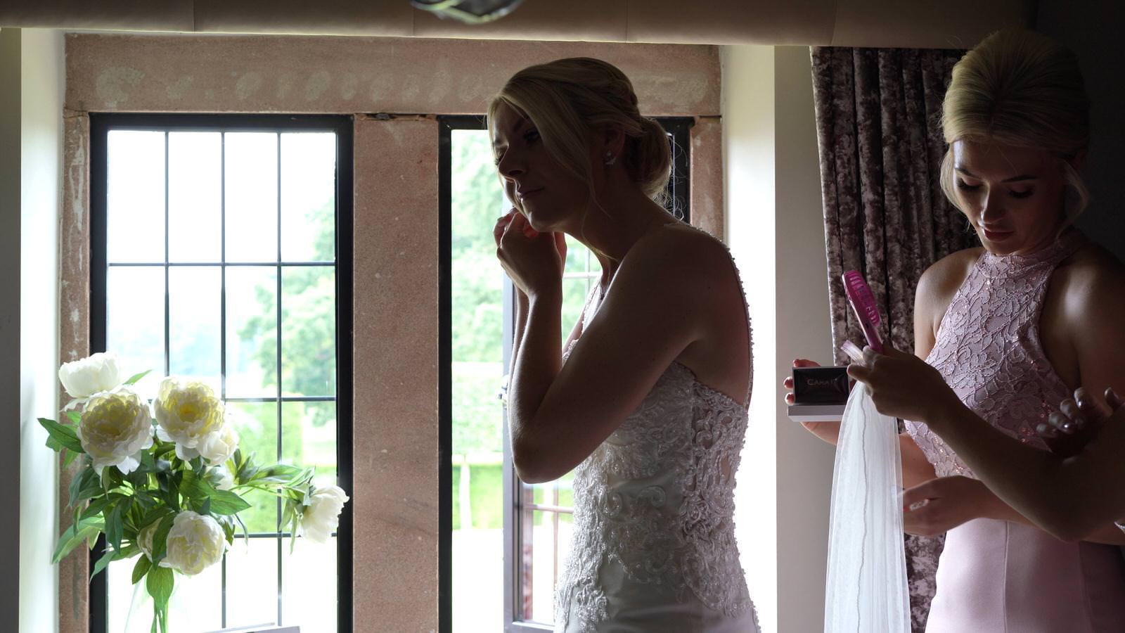 bride puts in earrings in window of merrydale manor