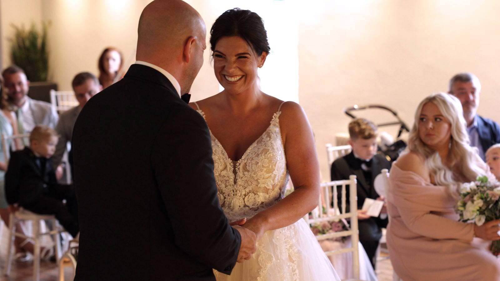 bride smiles at groom as they exchange wedding rings