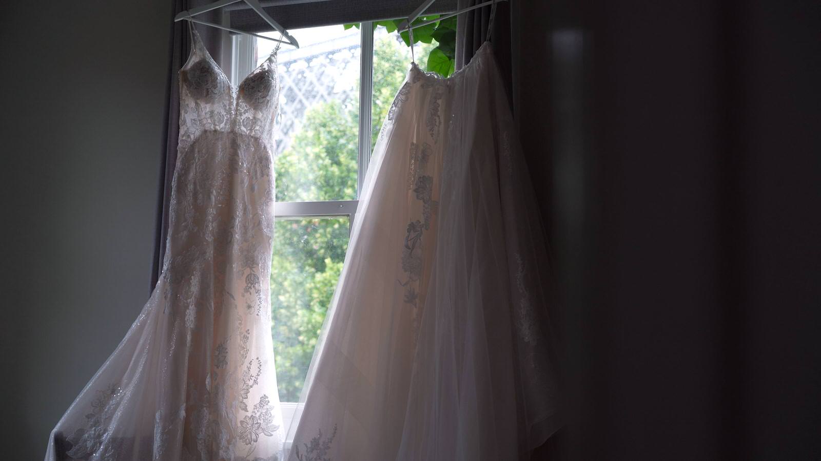 wedding dress and overskirt hangs in window