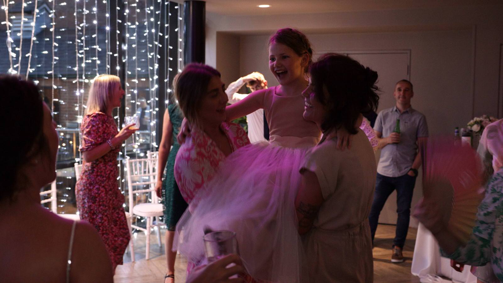 little bridesmaid gets lifted up on dancefloor