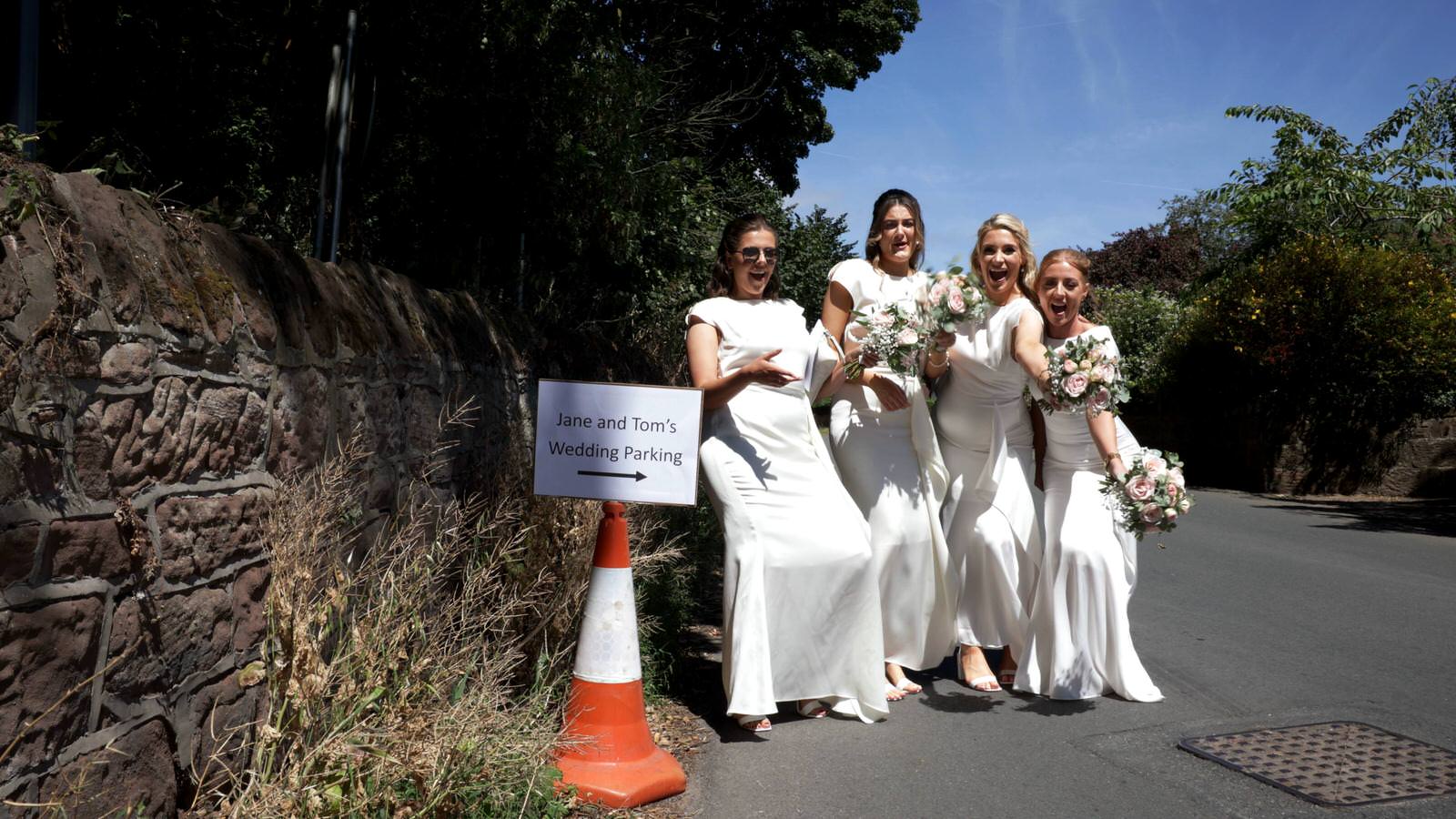 bridemaids pose outside village hall wedding sign